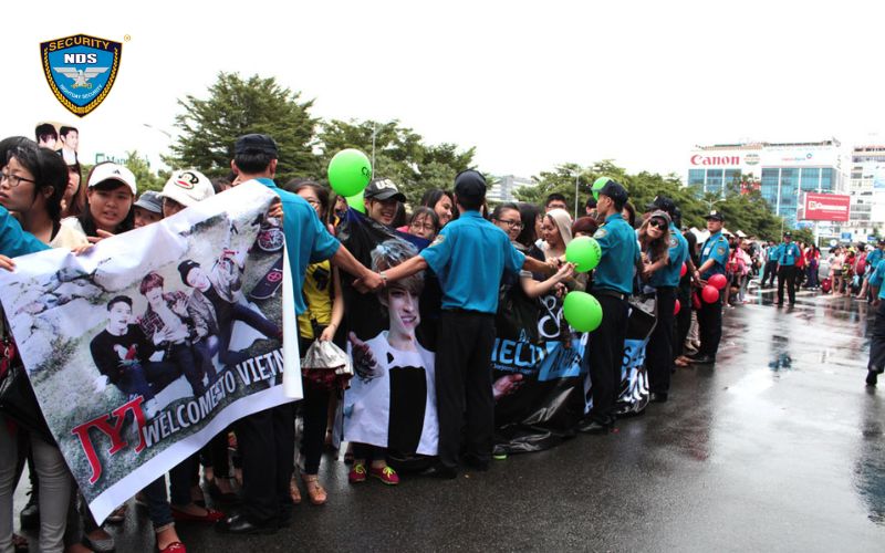 Nhân viên bảo vệ của công ty Bảo vệ Ngày và Đêm đội mưa cùng fan của JYJ khi nhóm nhạc nam Hàn Quốc đến Việt Nam